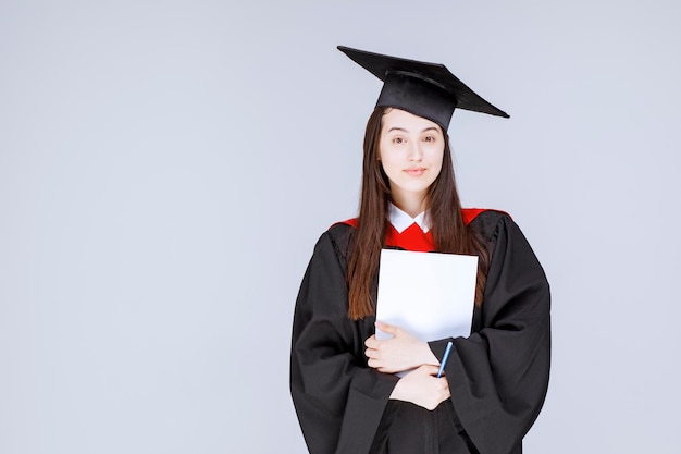 Graudate student with paper and pen standing before the ceremony starts. High quality photo