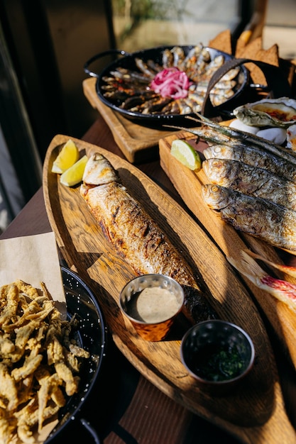 Foto pesce intero alla griglia servito con salse e frutti di mare fritti e croccanti. piatto di frutti di mar per gli amanti della cucina gourmet.