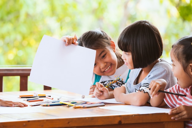 Photo group of asian children drawing and painting with crayon together with fun