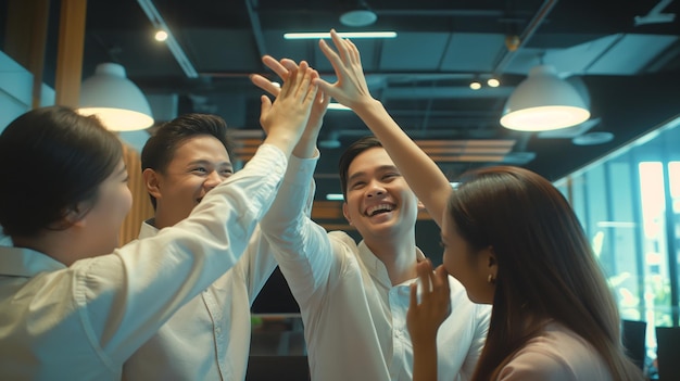 Photo a group of young asian office workers giving high fives in the air having fun and laughing together