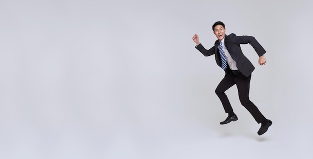 Handsome happy energetic young Asian businessman jumping in mid air