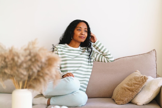 Happy africanamerican woman sitting on sofa in living room