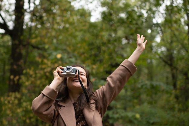 Happy caucasian woman taking photos using camera in the forest