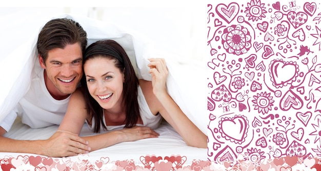 Happy Couple lying on bed against valentines pattern