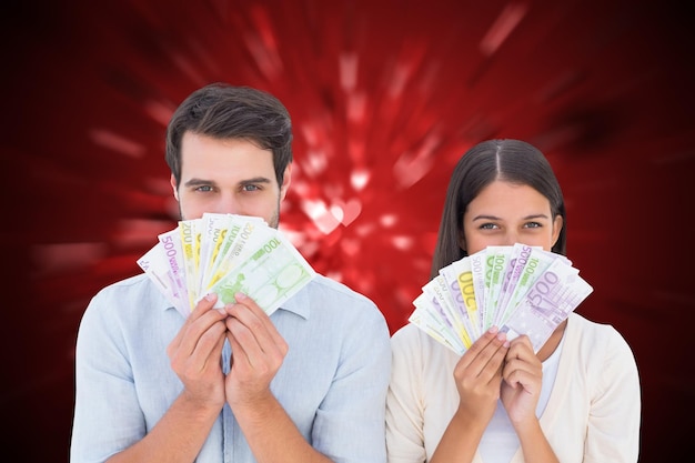 Happy couple showing their money against valentines heart design