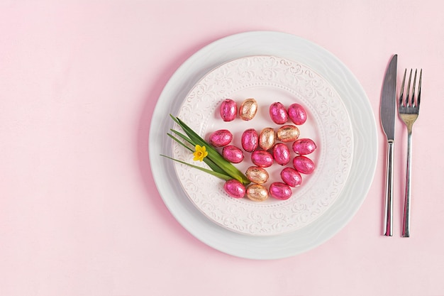 Happy Easter Table setting for Easter holiday Easter eggs flower and cutlery on pink background Top view flat lay