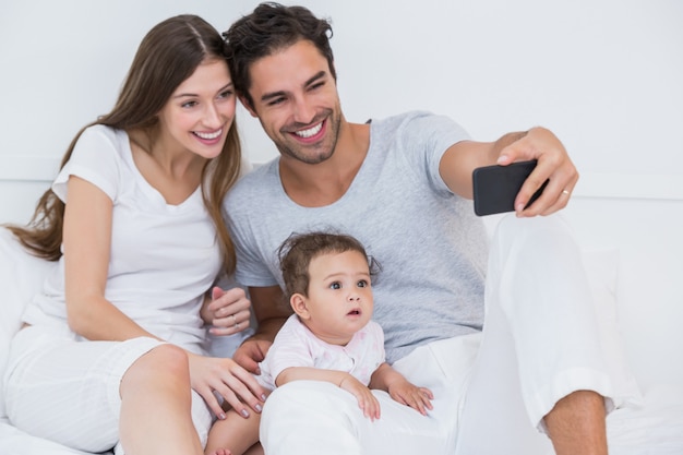 Happy family clicking selfie on bed 