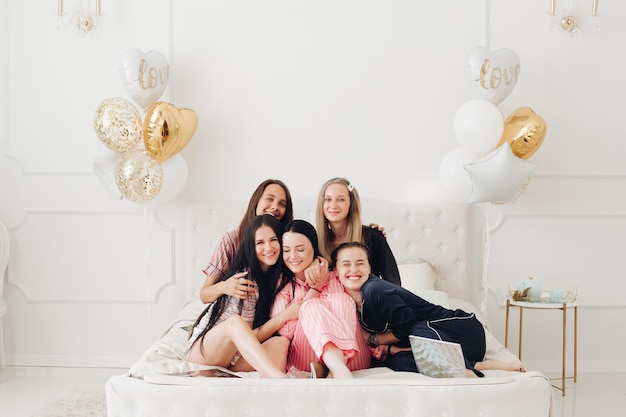 Happy pretty female friends sitting on the edge of the bed