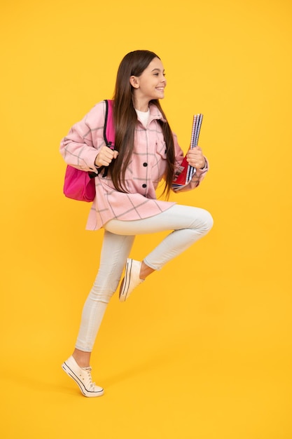 happy teen girl wear pink checkered shirt running with school bag and notebooks, runner.