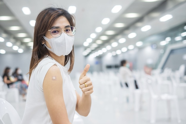 Photo happy woman showing thumb after receiving vaccine. vaccination, immunization, inoculation and coronavirus ( covid-19 ) pandemic