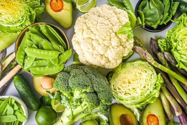 Healthy Diet Spring food background. Assortment of fresh raw organic green vegetables - broccoli, cauliflower, zucchini, cucumbers, asparagus, spinach, avocado, cabbage set on white background