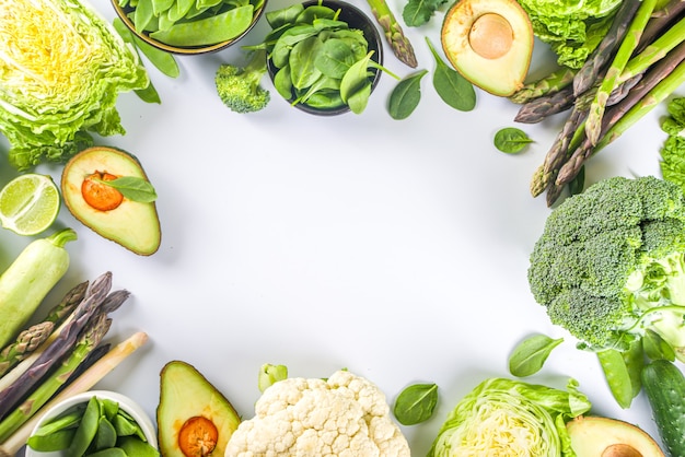 Healthy Diet Spring food background. Assortment of fresh raw organic green vegetables - broccoli, cauliflower, zucchini, cucumbers, asparagus, spinach, avocado, cabbage set on white background