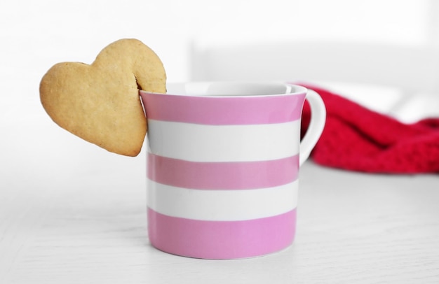 Photo heart shape cookie on cup of coffee on table closeup