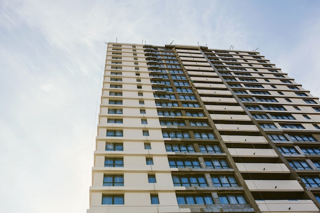 High unfinished modern building with windows. Construction and mortgage