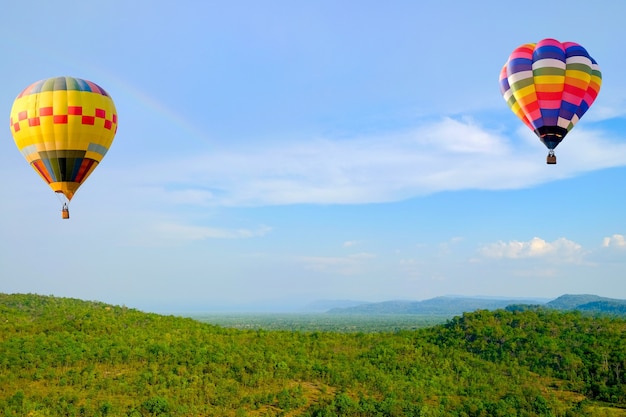 Hot-air Balloon floating in the sky near a rainbow over the mountains.