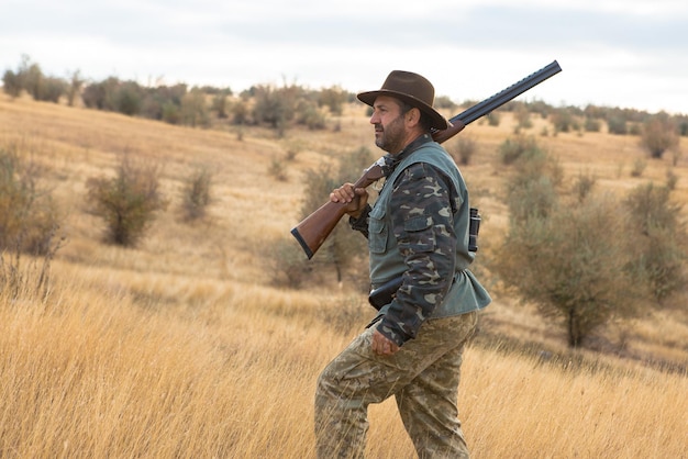 Hunter man in camouflage with a gun during the hunt in search of wild birds or game