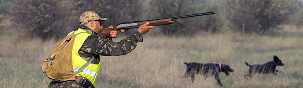 Hunter man in camouflage with a gun during the hunt in search of wild birds or game