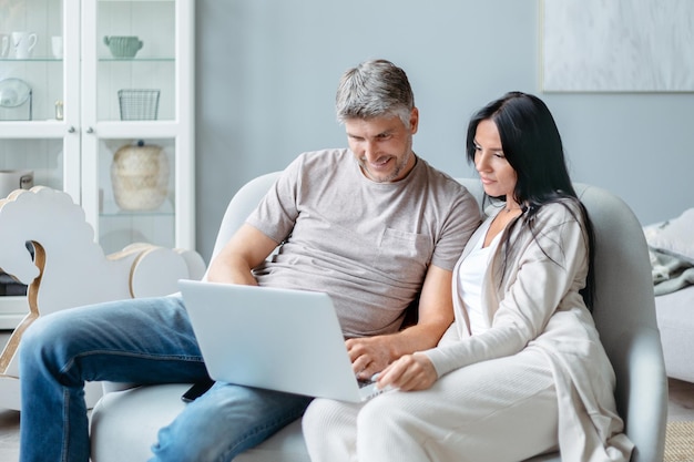 Husband and wife using a laptop in their living room