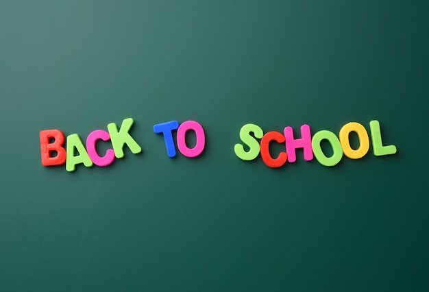 Photo inscription back to school from multicolored plastic letters on green chalk board