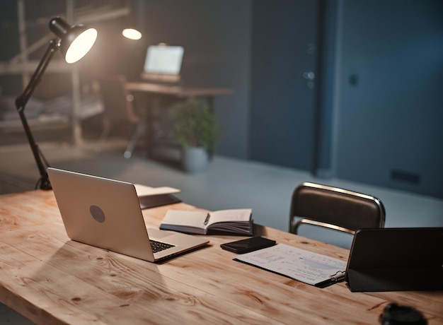 Interior of a night office with a desk and an open laptop