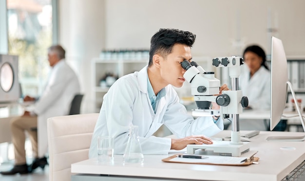 Photo investigation science and microscope with an asian man doctor working in a lab for research or innovation healthcare medical and experiment with a male scientist in a laboratory for analysis