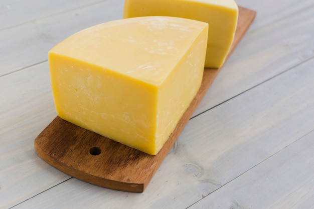 Photo italian cheese on wooden chopping board over the desk