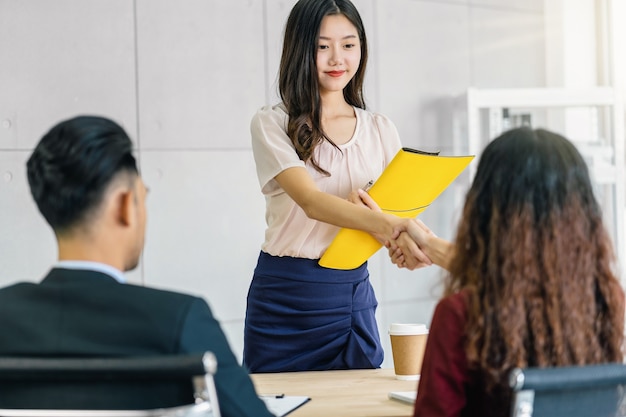 Foto jonge aziatische vrouw afgestudeerde handdruk met twee manager om te verwelkomen voordat ze aan een sollicitatiegesprek beginnen