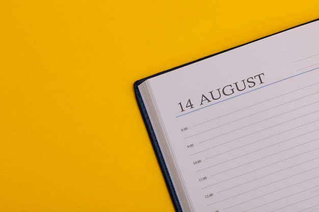 Foto kladblok of agenda met de exacte datum op een gele achtergrond kalender voor 14 augustus zomertijd ruimte voor tekst