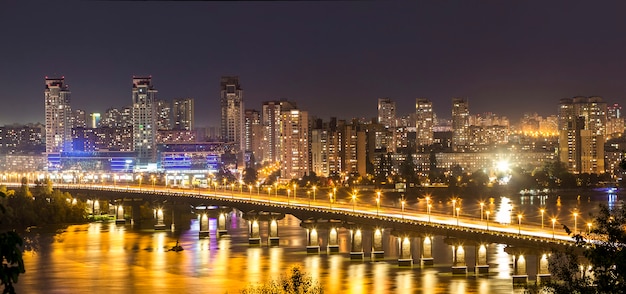 Kyiv (Kiev) city, the capital of Ukraine at night beside the Dnipro (Dniepr) river with reflection in water