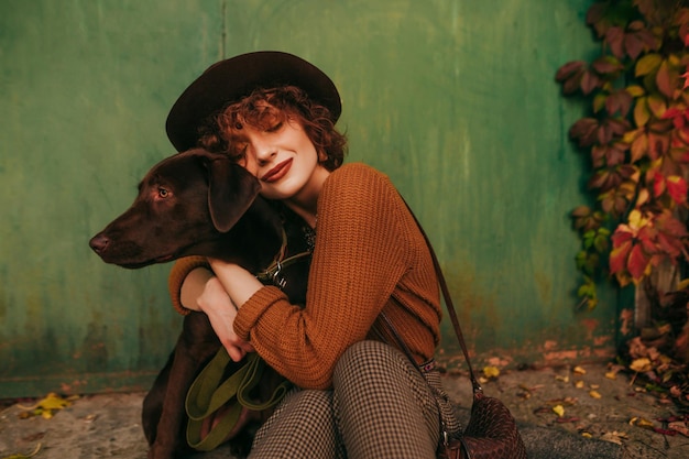 Lady sitting on the street near a country house with a pet