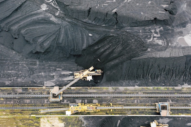 Photo large reserves of coal at a power plant, many cranes unloading coal, a lot of coal, top view