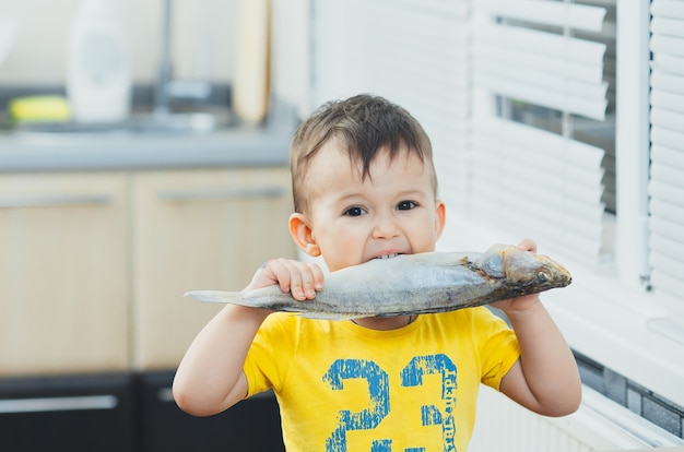 The little boy shows what a big fish he caught in the river. The concept of organic food.