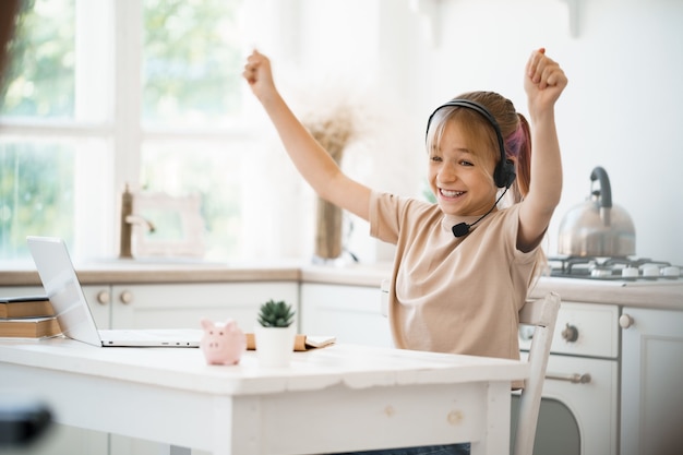 Little caucasian girl in headphones have video call distant class with teacher at home