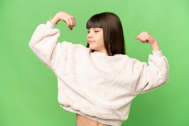 Photo 孤立した緑色の鍵の背景の上にある小さな女の子が強いジェスチャーをしています