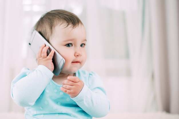 A little girl talking on a smartphone smiling and happy