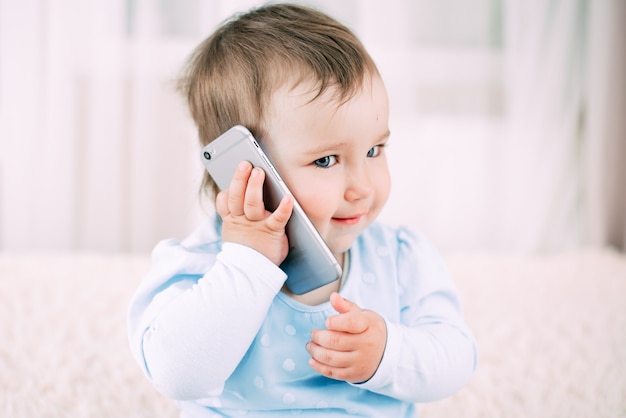 A little girl talking on a smartphone smiling and happy