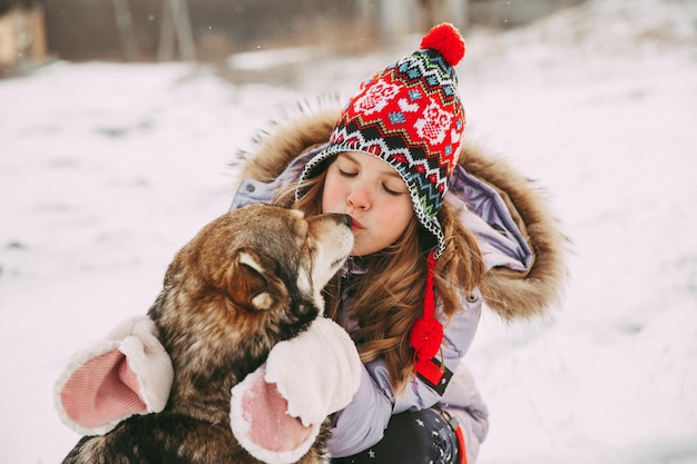 A little girl walks with her dog in the winter forest.