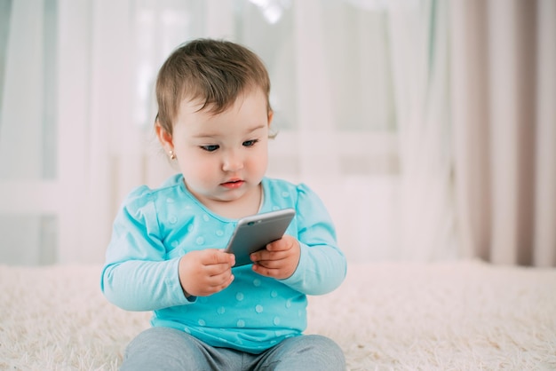 A little girl with a smartphone phone in her hands sits and presses very sweet