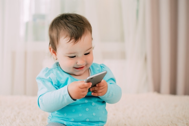 A little girl with a smartphone phone in her hands sits and presses