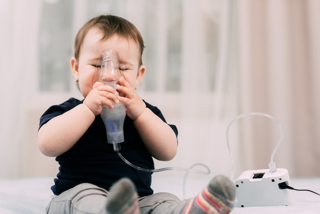 a little girl yourself holding the mask of the nebulizer, making inhalation and treated