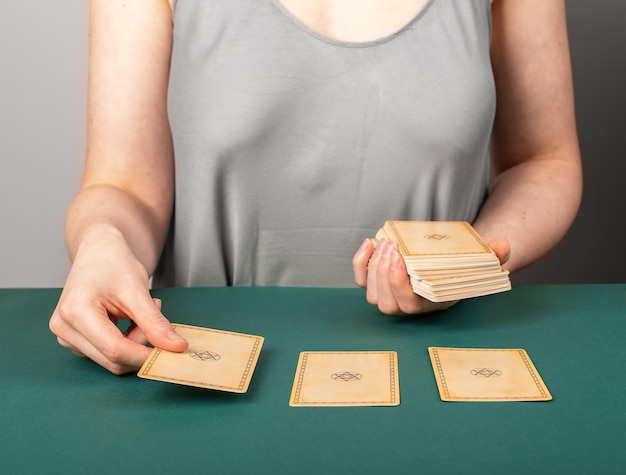 Lodz Poland April 15 2023 Tarot reader fortune teller spreading three taro cards on green table for fortune telling