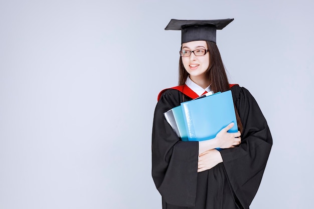 Long haired student in glasses folders in her hand standing. High quality photo