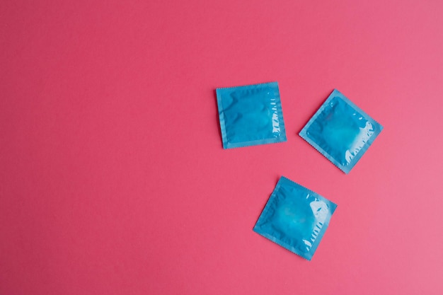 Photo lots of blue packages of unopened condoms on a pink background condom use reduces the likelihood of pregnancy or sexually transmitted diseases stis the concept of safe sex and reproductive health