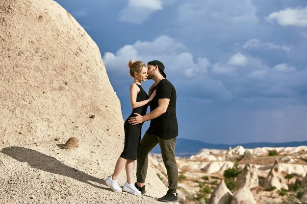 In love Eastern couple in mountains of Cappadocia hugs and kisses. Love and emotions loving couple vacationing in Turkey. Closeup portrait man and woman. Beautiful Crescent moon earrings on girl ears