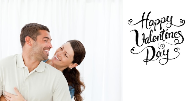 Lovely couple laughing together in the living room against happy valentines day