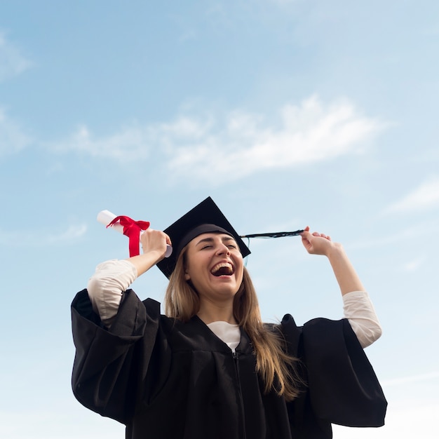 Low angle happy young woman celebrating her graduation