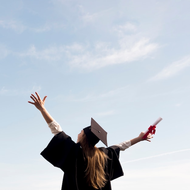 Low angle young woman celebrating her graduation