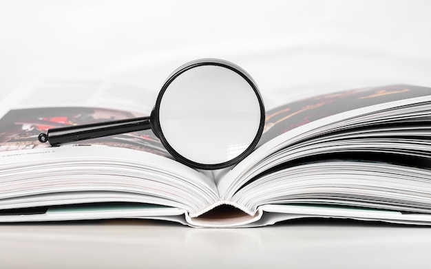 Magnifying glass over open paper art book with pages. Concept of academic research.