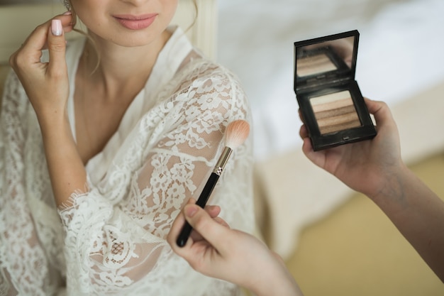 Photo makeup artist preparing bride before the wedding in a morning