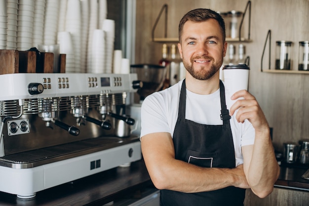 Male barista holding coffee in cardboard cup